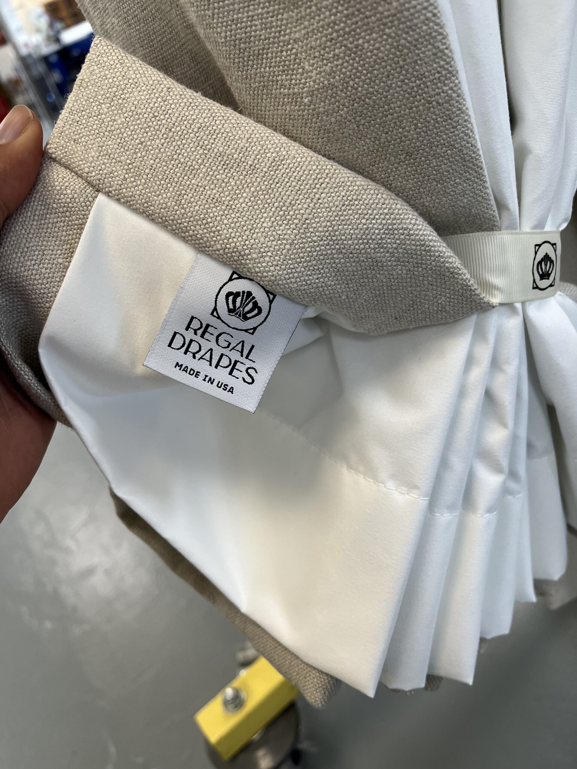 The back of a drapery panel, showing the hem, a woven Regal Drapes label, and a hem weight.