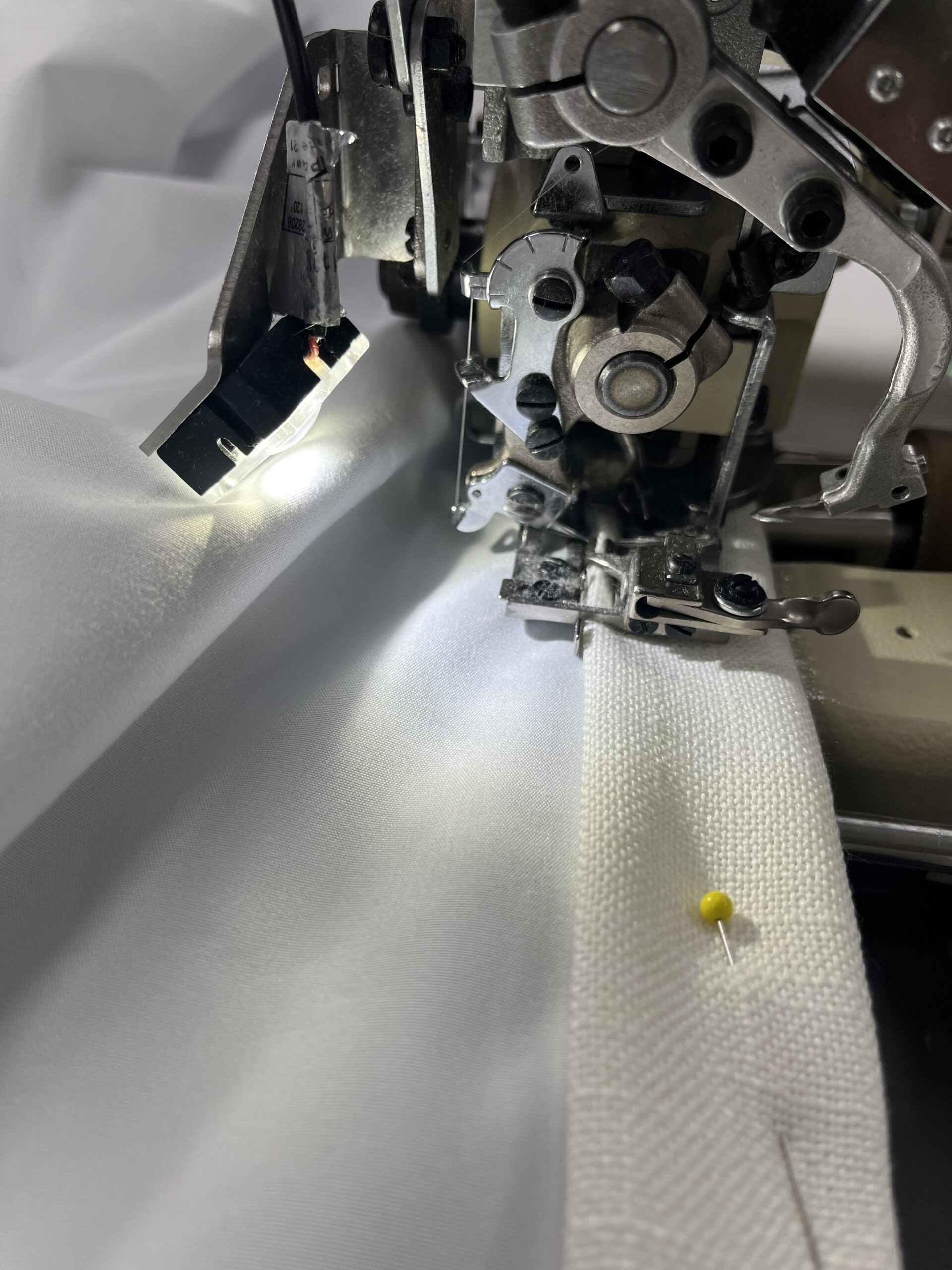 An industrial sewing machine blind-stitching a fabric hem.