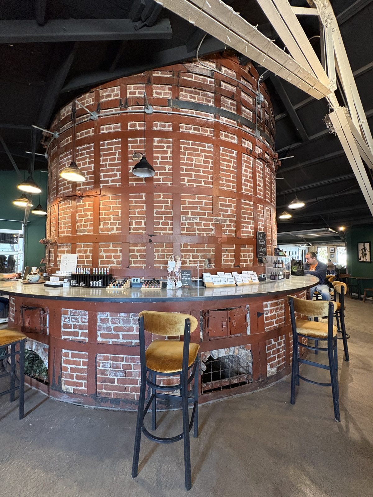 Alkemy Coffee Co., Flemington - a round brick structure in the middle of the room with a counter and bar stools