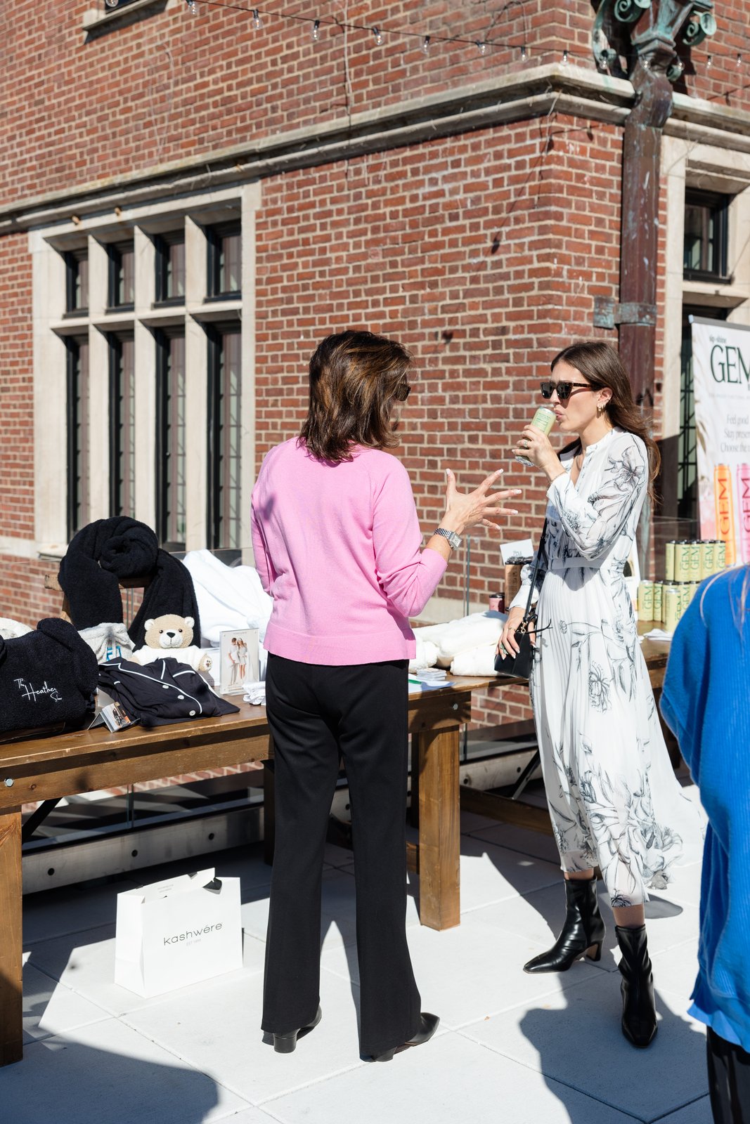 Boardrooms & Brunch, Pendry Natirar, Oct 9 2026 - two guests talking beside a vendor table of goods outside a brick building