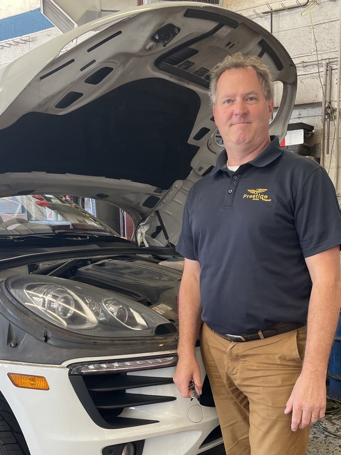 Jim Jackson of Prestige Auto Repair standing beside a car with its hood open.