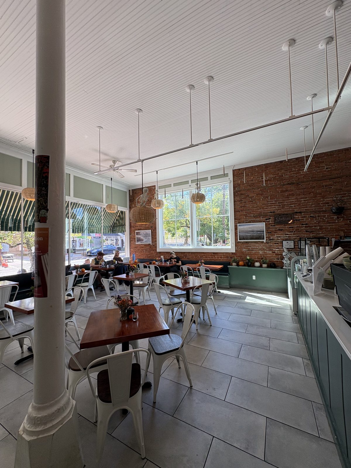 Jimmy's Coffeehouse, Clinton - the long room with white metal chairs, wood tables and a brick wall