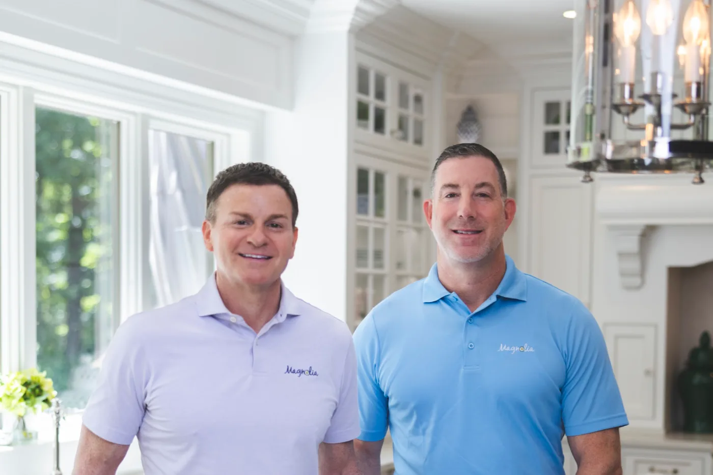 Chris Fontana and Vic Fiore standing side by side at a white kitchen island, both smiling, wearing Magnolia polo shirts