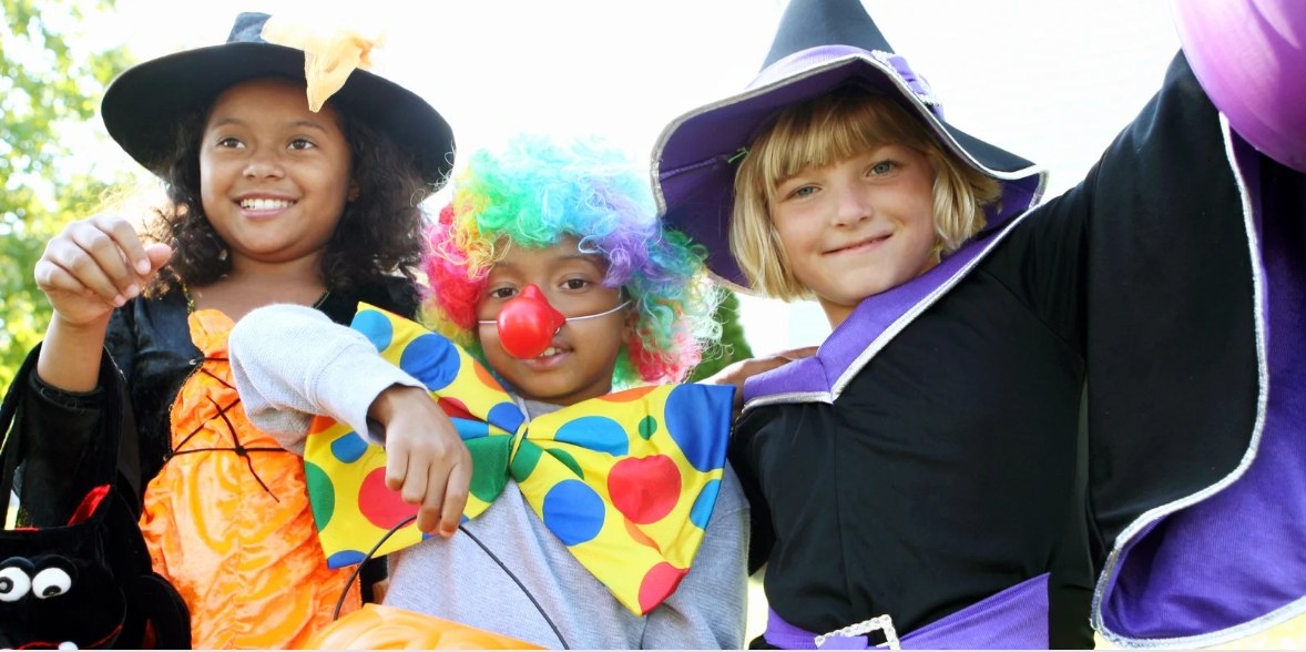 Three children in colorful Halloween costumes at Pier Village's Halloween Spooktacular.