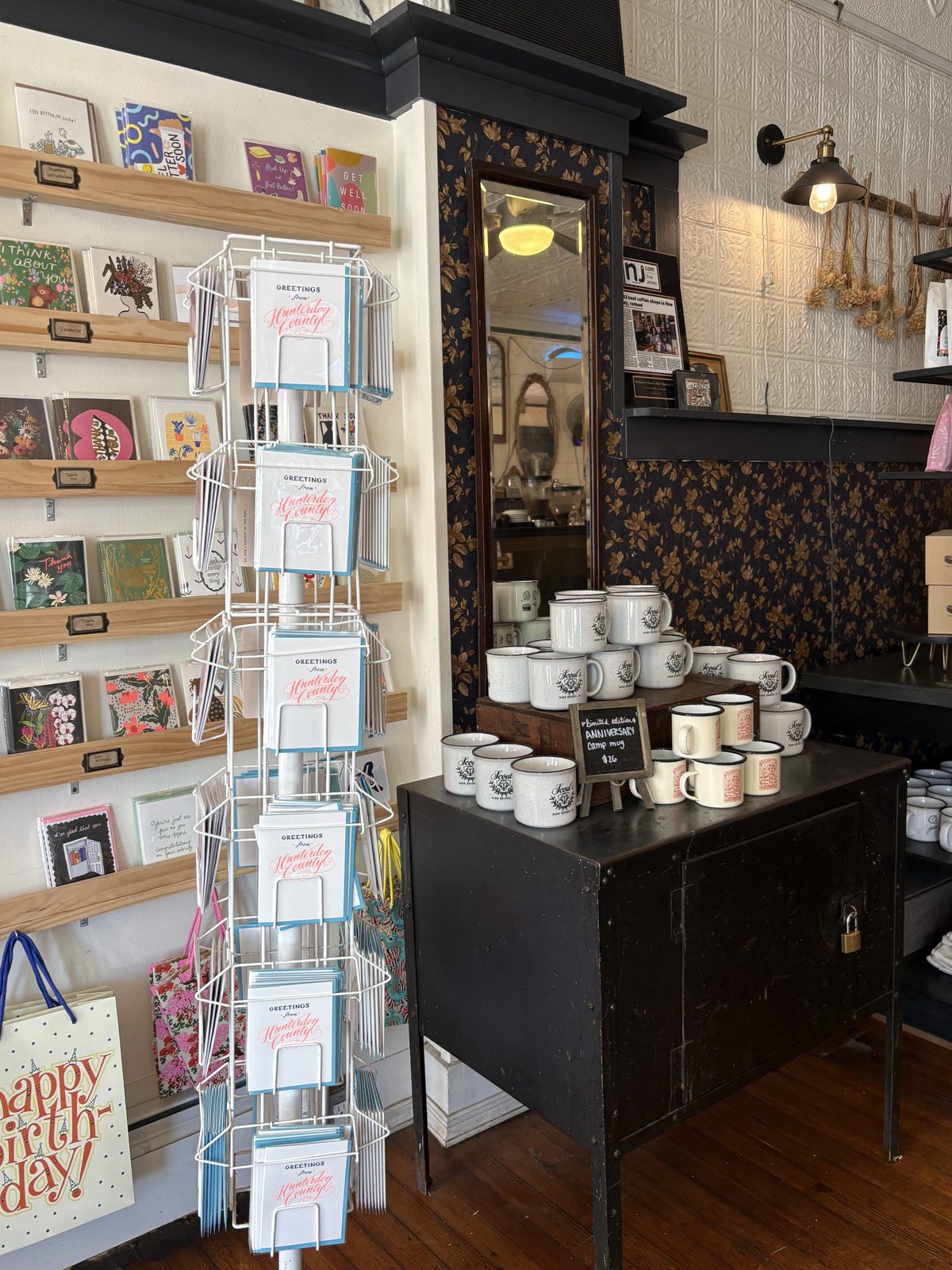 Scout's Coffee Bar + Mercantile, High Bridge - a card rack, a wall of greeting cards and a table of enamel mugs