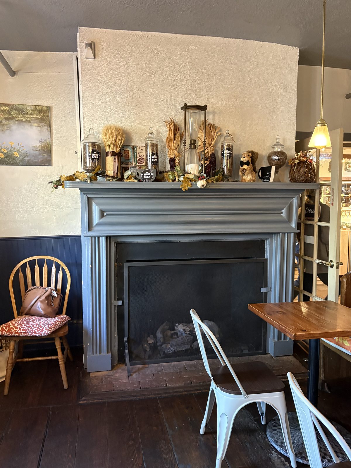 The Stone Bean, Clinton - the front room with a gray mantel fireplace and wood tables